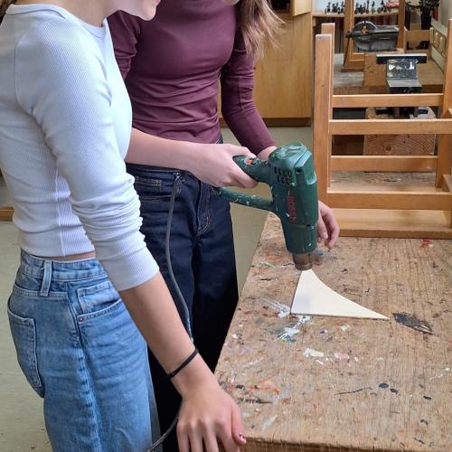 2 Schülerinnen mit Schutzbrillen beim Erhitzen des Holzes