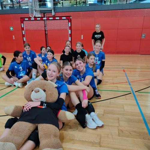 Schülerinnen sitzend mit Maskottchen