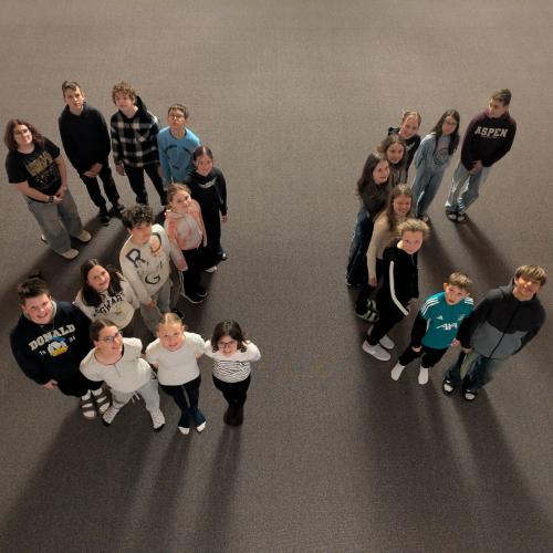 Kinder in der Aula bilden die Formen 2c