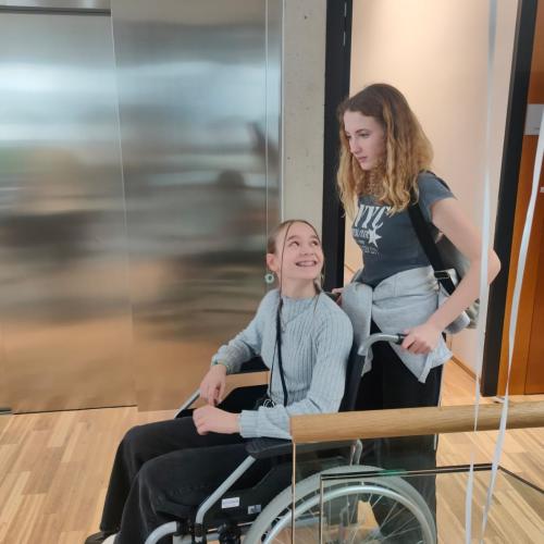 Schülerin im Rollstuhl, andere schiebt