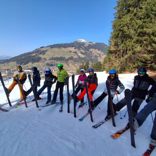 Schülergruppe auf der Piste mit aufgestellten Skiern