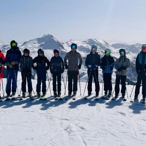 Schülergruppe auf der Piste mit Bergpanorama im Hintergrund