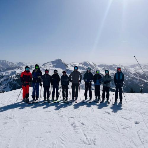 Schülergruppe auf der Piste mit Bergpanorama im Hintergrund
