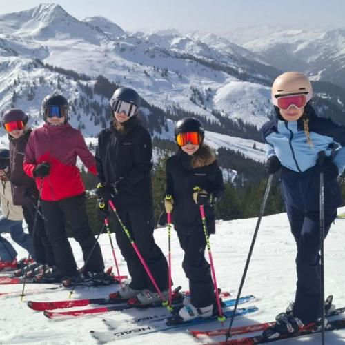 Schülergruppe auf der Piste mit Bergpanorama im Hintergrund