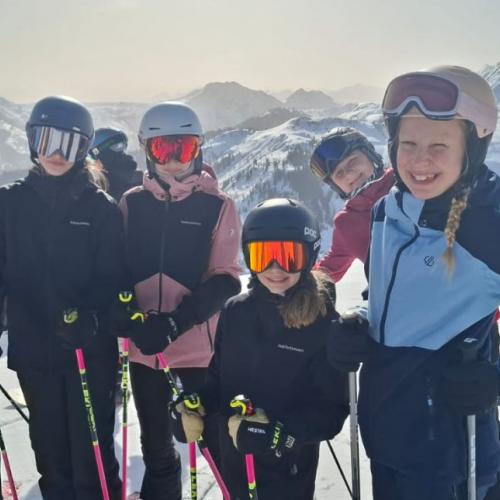 Schülergruppe auf der Piste mit Bergpanorama im Hintergrund