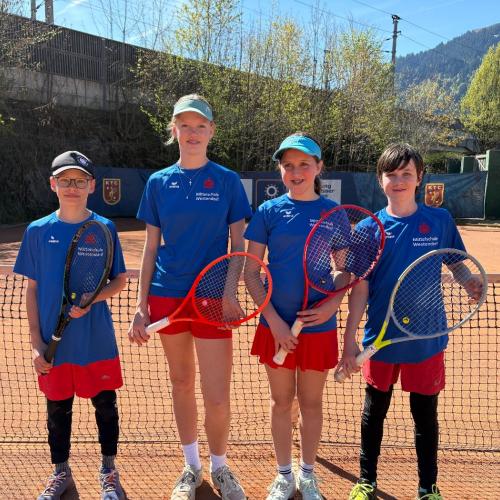3 Kinder am Tennisplatz mit Schläger vor Netz 