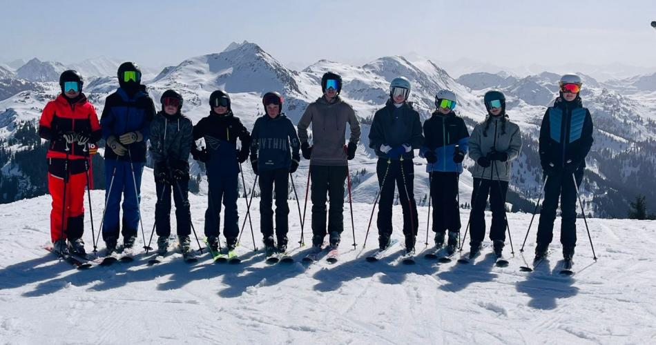 Schülergruppe auf der Piste mit Bergpanorama im Hintergrund